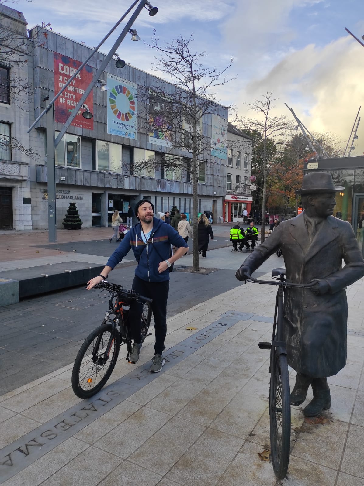 Tom with a bicycle beside a bronze cyclist statue in Cork city